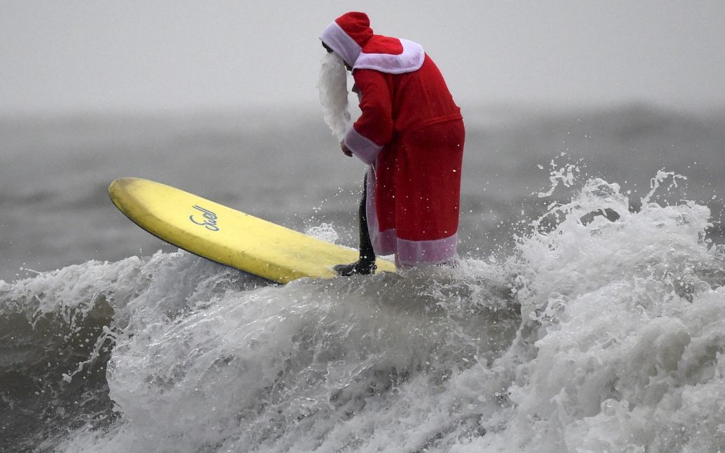 Серфер бере участь у змаганнях серферів у костюмах Санта-Клауса в Гауер, Уельс. / © Reuters