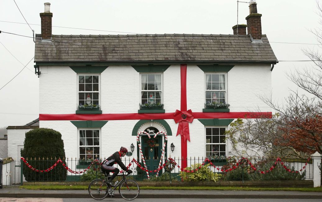Чоловік їде на велосипеді повз будинок, прикрашений наче різдвяний подарунок, у містечку в північній Англії. / © Reuters