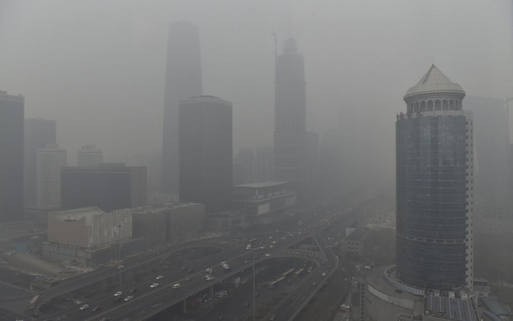 Транспорт едет на мосту в центральном деловом районе Пекина на фоне тяжелого смога после того как город впервые в истории достиг "красного уровня" загрязнения воздуха. / © Reuters