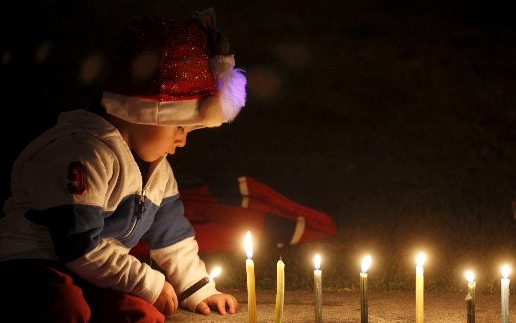 Ребенок зажигает свечи в парке Симона Боливара в Боготе, Колумбия. В эти дни каждый год колумбийцы зажигают свечи, чтобы отметить начало рождественских праздников. / © Reuters
