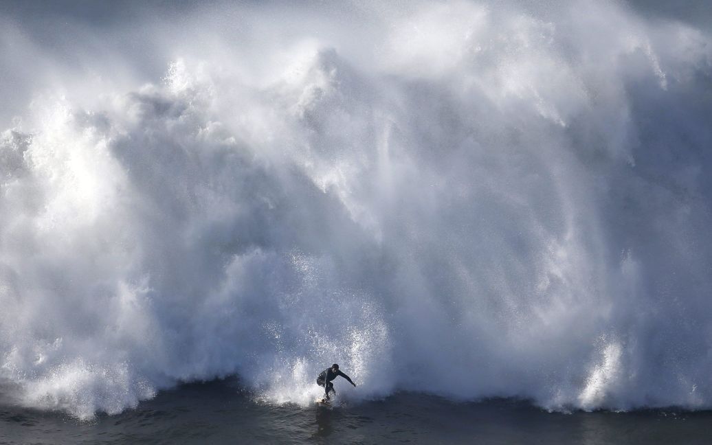 Серфер спускається по великій хвилі на пляжі Прайя-ду-Норте в Назаре, Португалія. Цей пляж став популярним серед серферів по всьому світу завдяки величезній висоті хвиль, які там утворюються. У 2011 році гавайський серфер Гарретт Макнамара встановив тут світовий рекорд, осідлавши хвилю висотою 30 метрів. / © Reuters