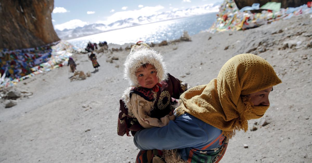 Тибетська жінка несе дитину під час відвідин озера Намцо в Тибетському автономному районі Китаю. Озеро розташоване у чотирьох годинах їзди від Лхаси на висоті близько 4718 метрів над рівнем моря. Намцо не лише найвище солоне озеро у світі, але також вважається священним, залучаючи натовпи віруючих і паломників. / © Reuters