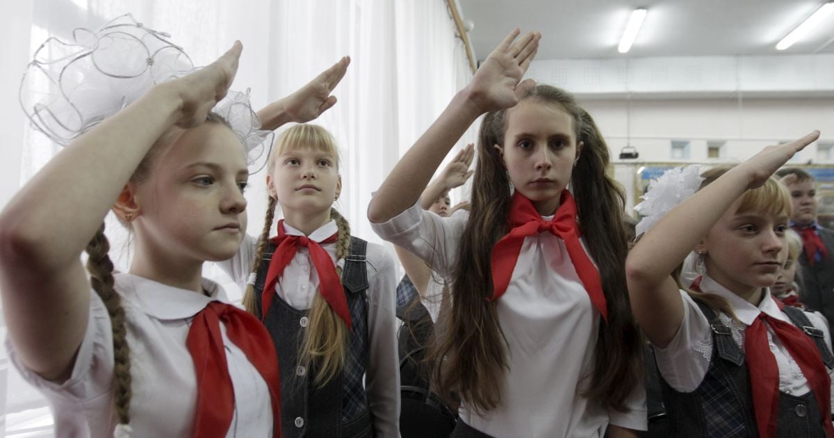 Діти, одягнені в червоні хустки, салютують під час церемонії вступу у піонери 18 нових членів у місцевій школі в селищі Казьминське у Ставропольському краї, Росія. У той час як СРСР-івська піонерська організація втратила свій вплив серед студентів в пострадянській Росії, деякі освітні установи і сім'ї продовжують нести цю традицію. / © Reuters