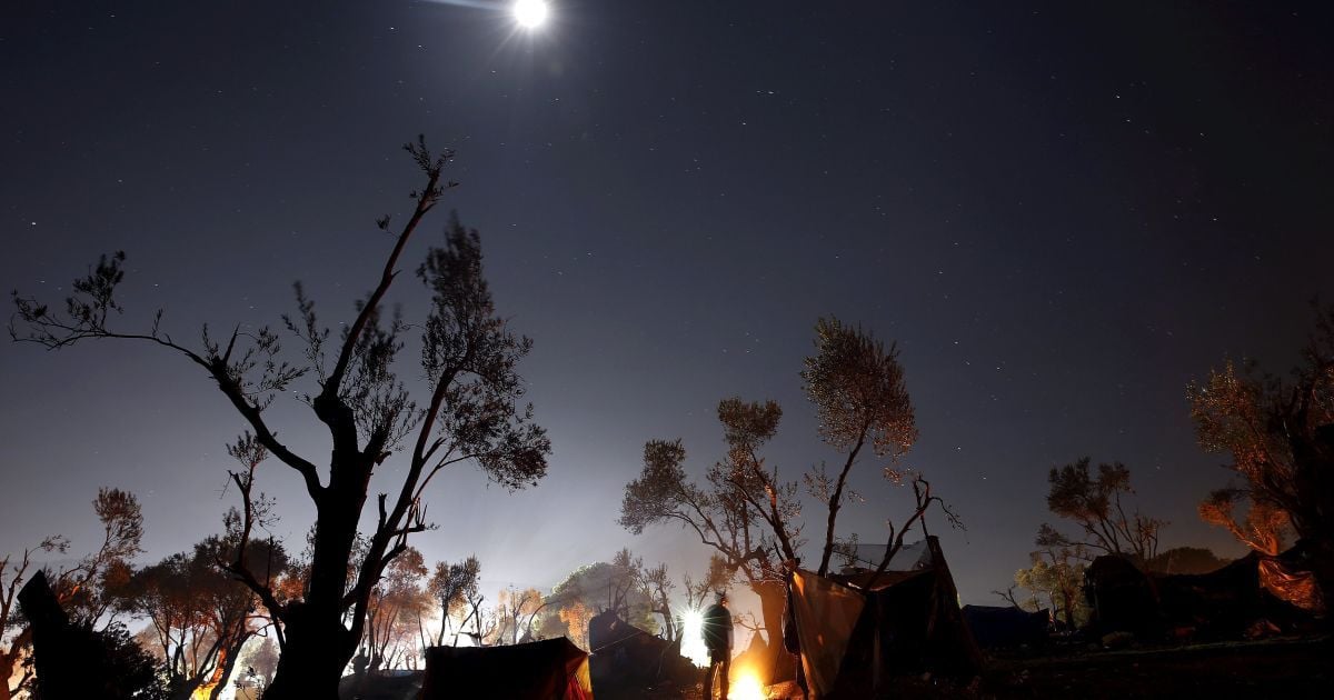 Біженець гріється біля вогню у таборі поруч із реєстраційним центром на грецькому острові Лесбос. Управління з питань біженців ООН звернулося до грецької влади із проханням створити додаткові приміщення для прийому мігрантів, оскільки зараз є лише 2800 місць, тоді як на острові знаходиться 12 тисяч біженців. / © Reuters