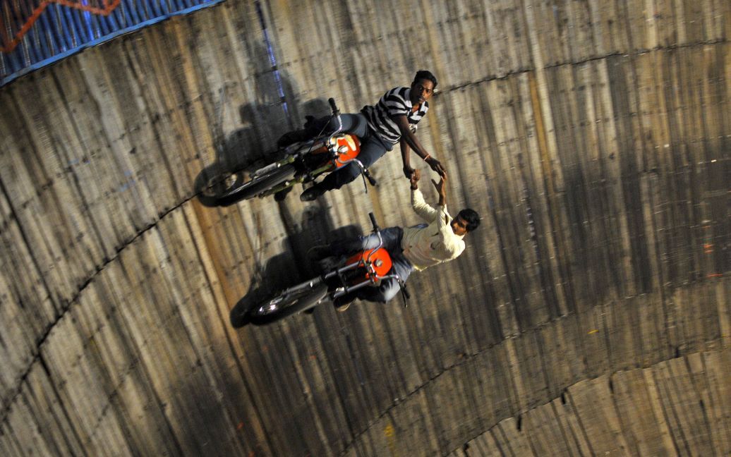 Виконавці трюків їздять на мотоциклах на стінах "Криниці смерті" на ярмарку на околиці Бангалорі, Індія. Цей атракціон привертає увагу великої кількості глядачів. / © Reuters
