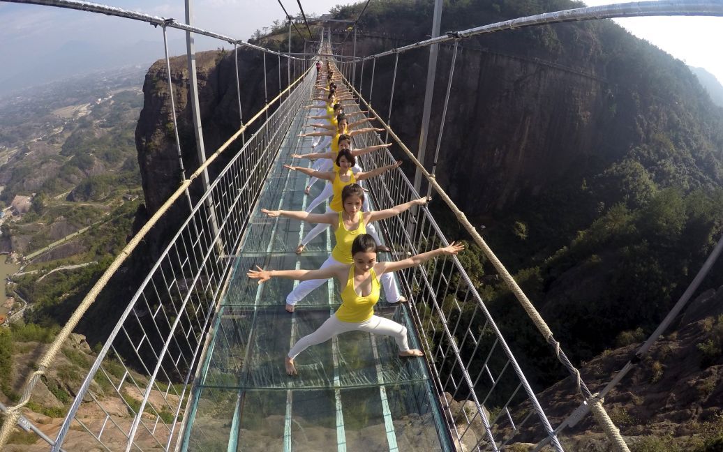 Жінки займаються йогою під час виступу на скляному мості у Національному парку Чжанцзяцзі у Китаї. Близько ста шанувальників йоги провели спільне заняття на мосту, щоб просувати концепцію зеленого життя і ідею гармонії між людиною і природою. Скляний підвісний мост у Чжанцзяцзі - найдовший у світі. Його довжина складає 275 метрів, він висить на висоті 182 метри. / © Reuters