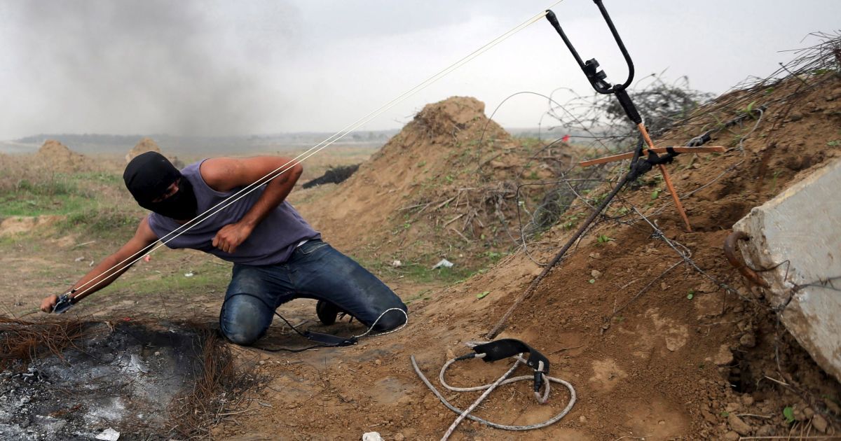 Палестинський демонстрант використовує рогатку для того, щоб жбурнути камені в ізраїльських військових під час зіткнень в районі кордону між Ізраїлем і сектором Газа. За час протистоянь між палестинцями та ізраїльською поліцією загинули 11 ізраїльтян та 69 палестинців, більшість з яких були нападниками. / © Reuters