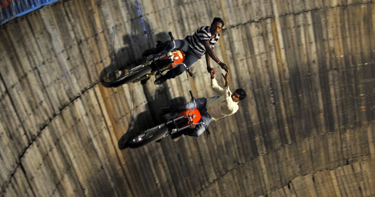 Виконавці трюків їздять на мотоциклах на стінах "Криниці смерті" на ярмарку на околиці Бангалорі, Індія. Цей атракціон привертає увагу великої кількості глядачів. / © Reuters