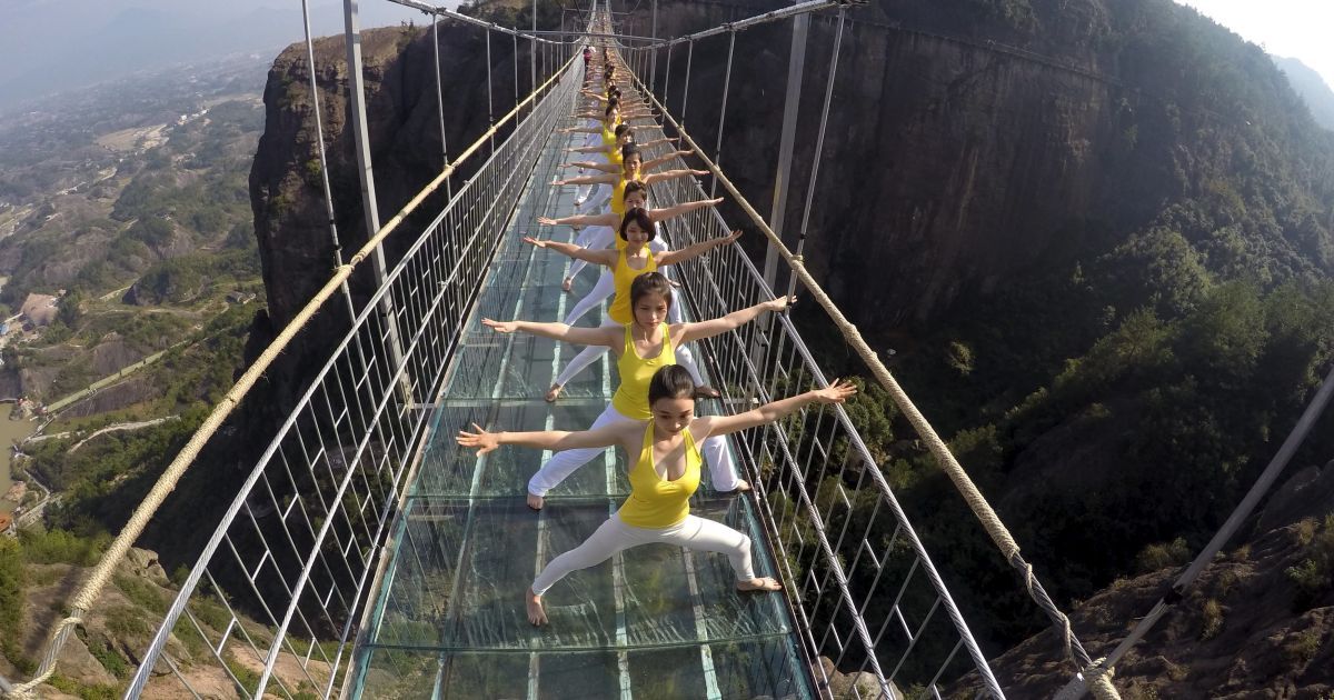 Жінки займаються йогою під час виступу на скляному мості у Національному парку Чжанцзяцзі у Китаї. Близько ста шанувальників йоги провели спільне заняття на мосту, щоб просувати концепцію зеленого життя і ідею гармонії між людиною і природою. Скляний підвісний мост у Чжанцзяцзі - найдовший у світі. Його довжина складає 275 метрів, він висить на висоті 182 метри. / © Reuters