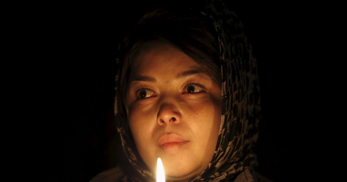 Жінка тримає свічку перед трунами семи хазарейців під час акції протесту в Кабулі, Афганістан. Сотні афганців вийшли на знак протесту проти вбивства хазарейців невідомими бойовиками. / © Reuters