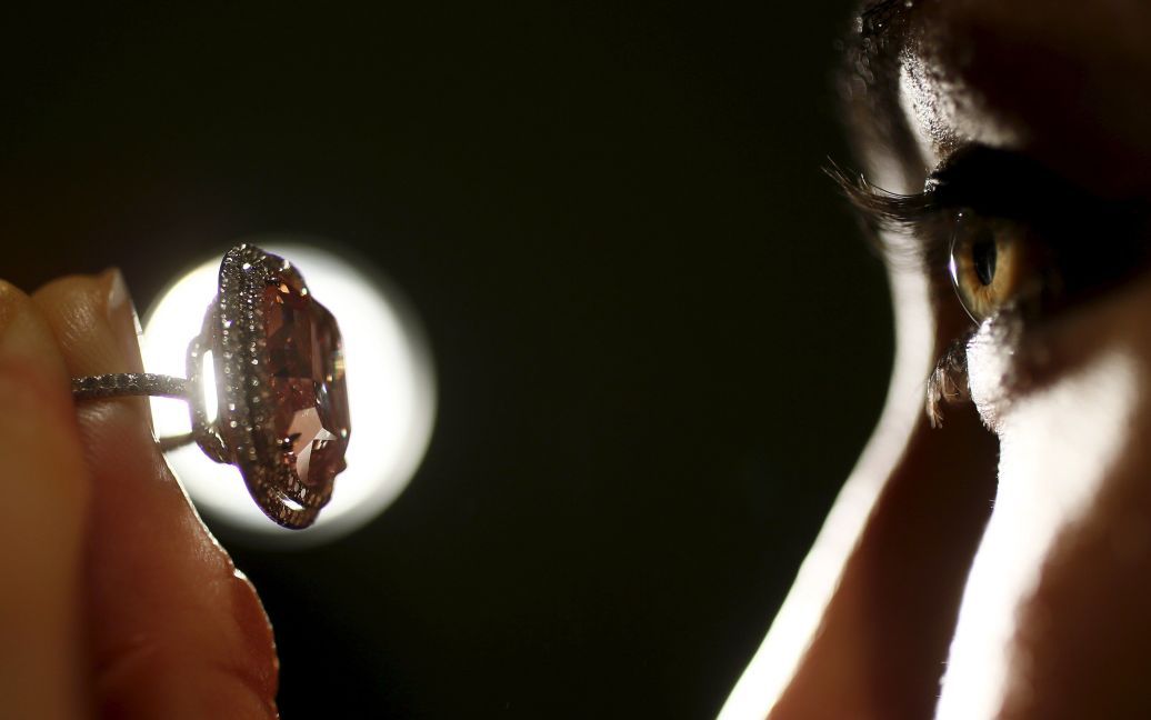 Співробітниця дивиться на перстень з яскравим рожевим діамантом 16.08 карат в аукціонному домі Крісті у Лондоні, Великобританія. Цей камінь планують продати за $ 23-28 млн на аукціоні в Женеві, який відбудеться 10 листопада. / © Reuters