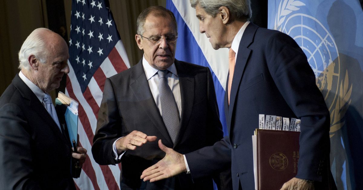 Спеціальний посланник ООН по Сирії Стаффан де Містура дивиться, як міністр закордонних справ Росії Сергій Лавров і держсекретар США Джон Керрі потиснути один одному руки після прес-конференції у Відні. 30 жовтня представники 19 країн провели зустріч, внаслідок якої випрацювали перші кроки з мирного врегулювання конфлікту у Сирії. / © Reuters