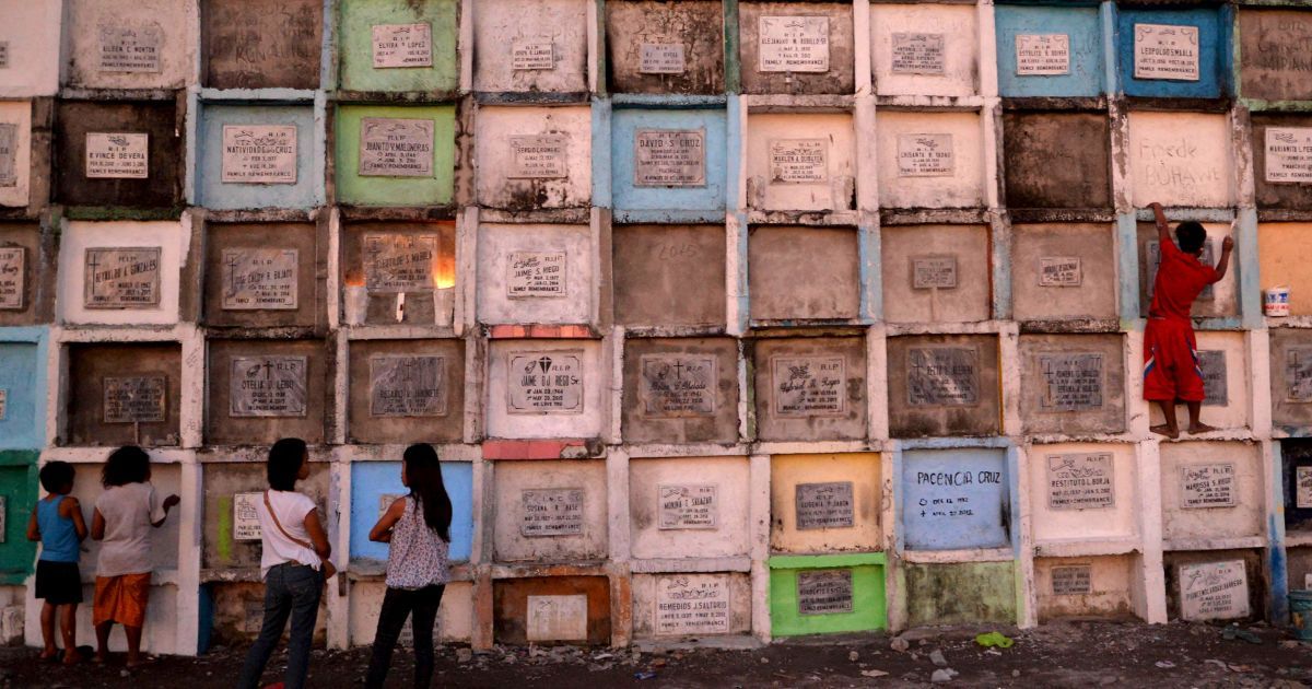 Работник городского кладбища перерисовывает могилу в городе Навотасе, к северу от Манилы. Филиппинцы готовятся к празднованию Дня всех святых 1 ноября, во время которого посещают могилы своих усопших родных и близких. / © Reuters