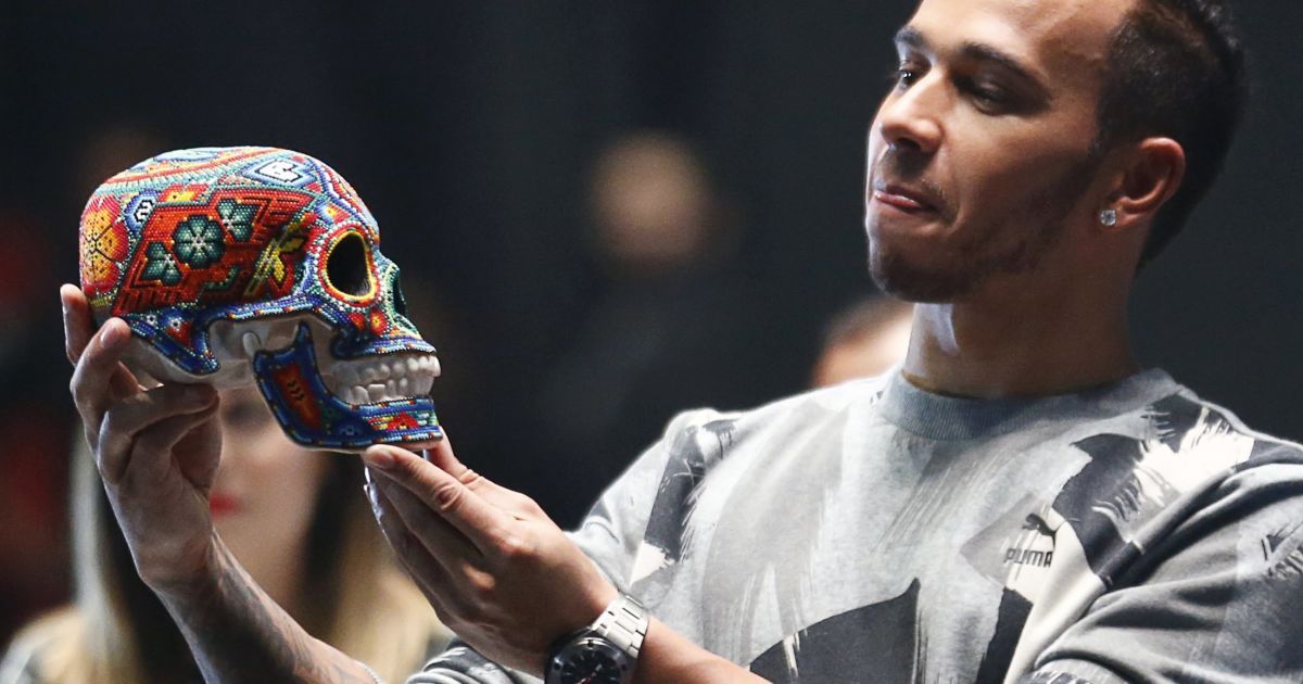 Гонщик команды "Мерседес" Формулы-1 Льюис Хэмилтон смотрит на традиционный для мексиканского Дня мертвых череп, украшенный местными ремесленниками, во время промо-акции в Мехико. Гран-при Формулы-1 вернется в Мексику 1 ноября. / © Reuters