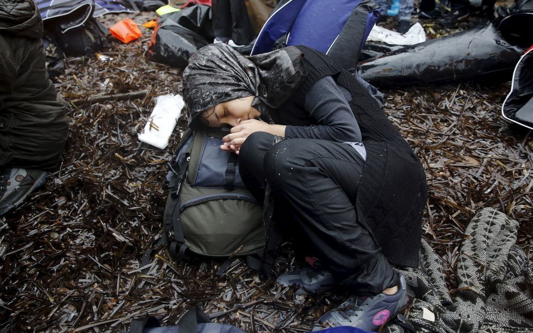 Сирийские беженцы отдыхают после того, как их лодка во время ливня прибыла на греческий остров Лесбос. Более полумиллиона беженцев и мигрантов прибыли по морю в Грецию в этом году и количество прибывших растет. / © Reuters
