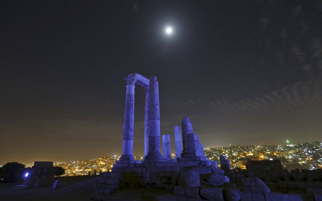 Луна видна сквозь римские колонны храма Геркулеса, которые светятся синим в честь 70-летия Организации Объединенных Наций в Цитадели Аммана, Иордания. / © Reuters