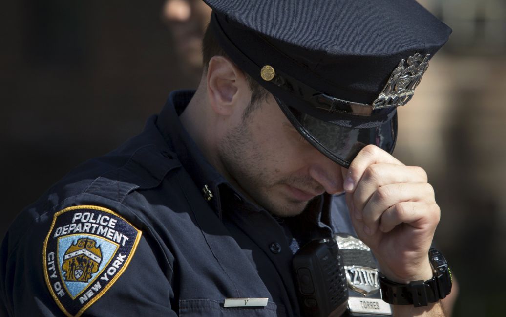 Офицер полиции Нью-Йорка склоняет голову у места убийства офицера Рэндольфа Холдера в Манхэттене. Холдер был застрелен поздно вечером во вторник во время преследования вооруженного грабителя. / © Reuters