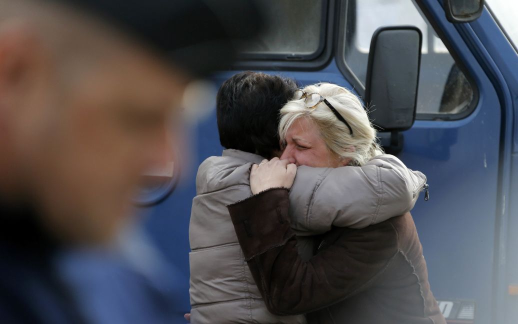 Люди утешают друг друга за пределами центра экстренной терапии во время спасательных операций в районе того места, где пассажирский автобус столкнулся с грузовиком близ города Бордо, Франция. В результате аварии погибли 42 человека. / © Reuters