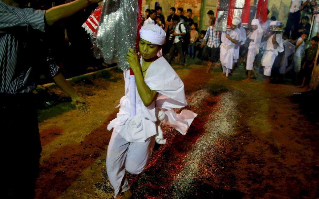 Шиитский мусульманин идет по горячим углям во время фестиваля Ашура в мечети в центре Янгона, Мьянма. Ашура является важнейшим днем ​​в шиитском календаре, который отмечается в память о смерти имама Хусейна, внука пророка Мухаммеда. / © Reuters