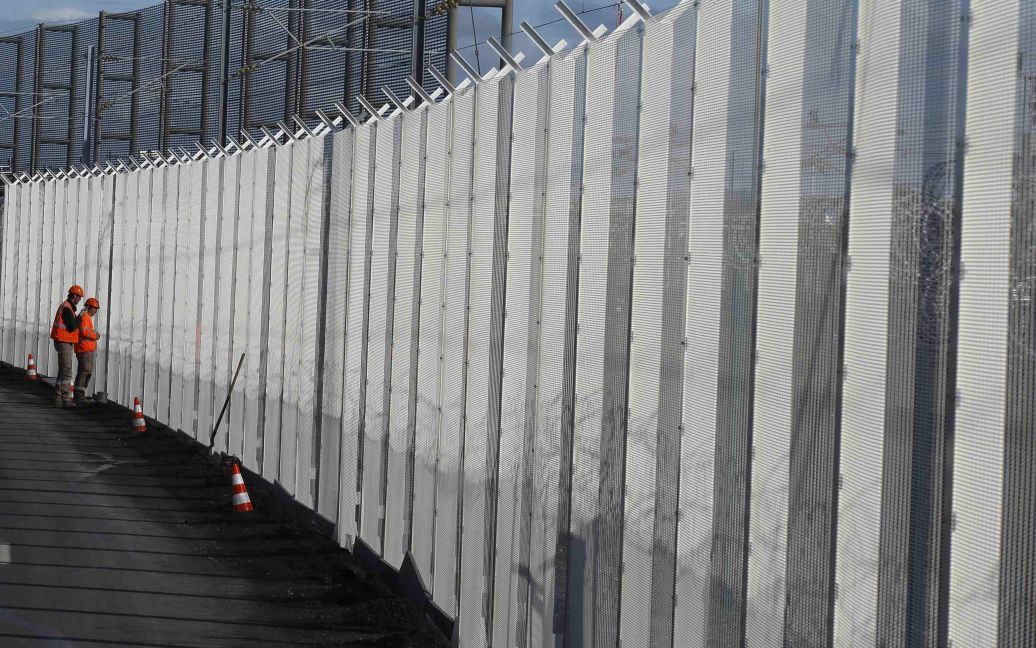 Рабочие строят новый забор неподалеку от французского города Кале, чтобы закрыть доступ мигрантам к Евротоннелю. Попытки беженцев перейти Ла-Манш через тоннель завершились несколькими смертями. / © Reuters