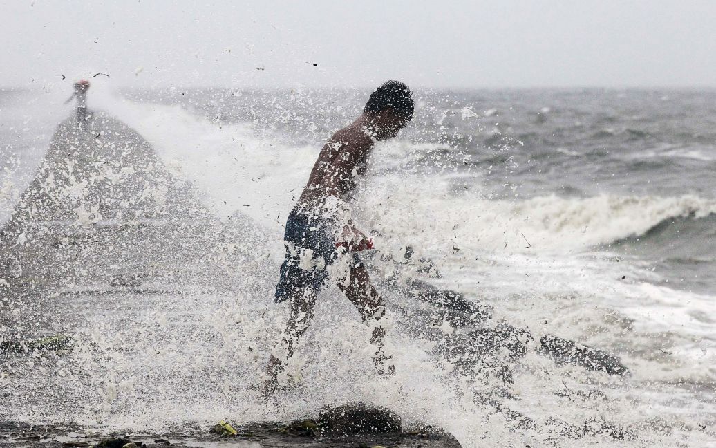 Мальчик ищет многократные пластиковые бутылки в волнах, принесенных тайфуном Коппу в Маниле, Филиппины. Мощный тайфун вынудил покинуть свои дома 10000 людей и причинил значительные разрушения. / © Reuters
