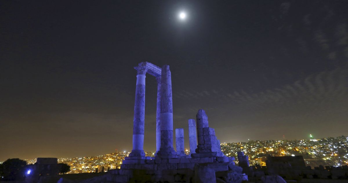 Луна видна сквозь римские колонны храма Геркулеса, которые светятся синим в честь 70-летия Организации Объединенных Наций в Цитадели Аммана, Иордания. / © Reuters