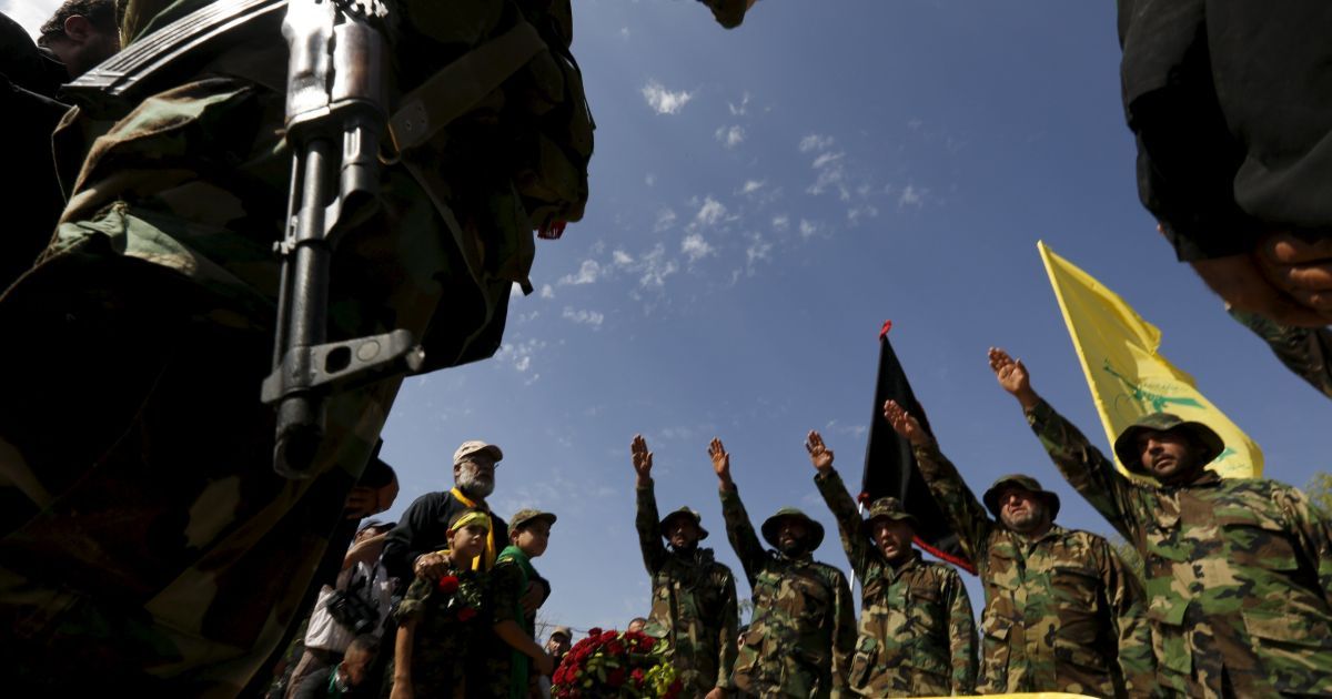 Члены ливанского движения "Хезболла" стоят с поднятыми руками над гробом их сподвижника Аббаса Хамуда во время его похорон в селе Кфар-Кила. Хамуд погиб бою с боевиками сирийской оппозиции в провинции Идлиб. / © Reuters