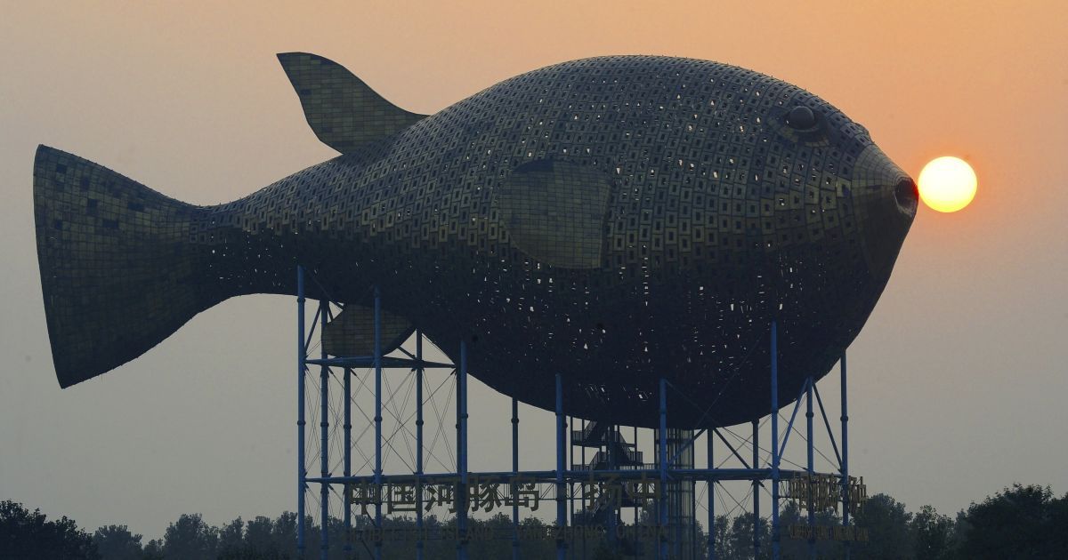 Солнце садится за смотровой башней в форме гигантской рыбы на берегу реки в округе Янгчонг провинции Цзянсу, Китай. Башня состоит из 8 920 медных пластин, она имеет высоту 15 метров. Ее изготовление стоило около 70 млн юаней ($ 11,4 млн). / © Reuters