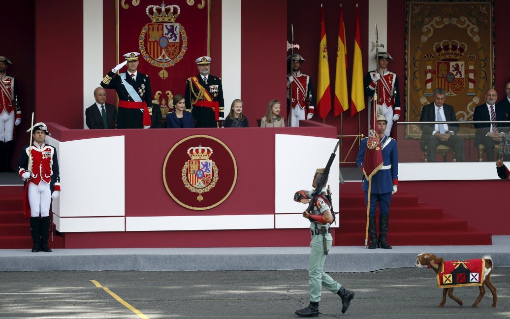 Коза, талісман іспанських легіонерів, іде перед іспанським королем Феліпе, королевою Летицією і їх дочками принцесами Леонорою та Софією під час військового параду на честь Національного дня Іспанії в Мадриді. / © Reuters