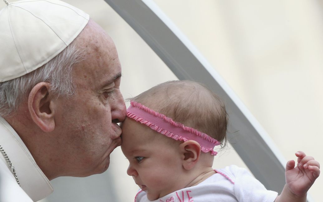 Папа Римский Франциск целует ребенка во время еженедельной аудиенции на площади Святого Петра в Ватикане. / © Reuters