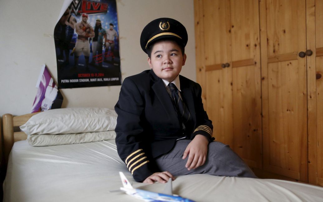 12-летний Скотт Чу позирует для фотографии в мундире своего отца, пилота рейса MH17 Евгения Чу, в своей спальне в Серембан, недалеко от Куала-Лумпур, Малайзия. 13 октября Совет безопасности Нидерландов обнародовал отчет, согласно которому самолет был сбит ракетой российского производства. / © Reuters