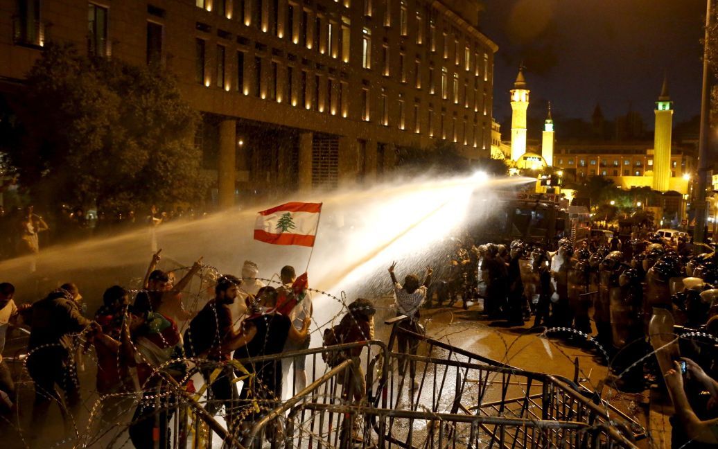 Ливанских демонстрантов опрыскивают водой во время акции протеста на площади Мартир в столице страны Бейруте. 8 октября ливанские силы безопасности открыли огонь из водометов по десяткам антиправительственных демонстрантов. Толпа скандировала: "Люди хотят падения режима", когда полиция окружила протестующих в центре города. В Ливане уже несколько недель продолжаются протесты из-за политического паралича, коррупции и плохой инфраструктуры в стране. / © Reuters