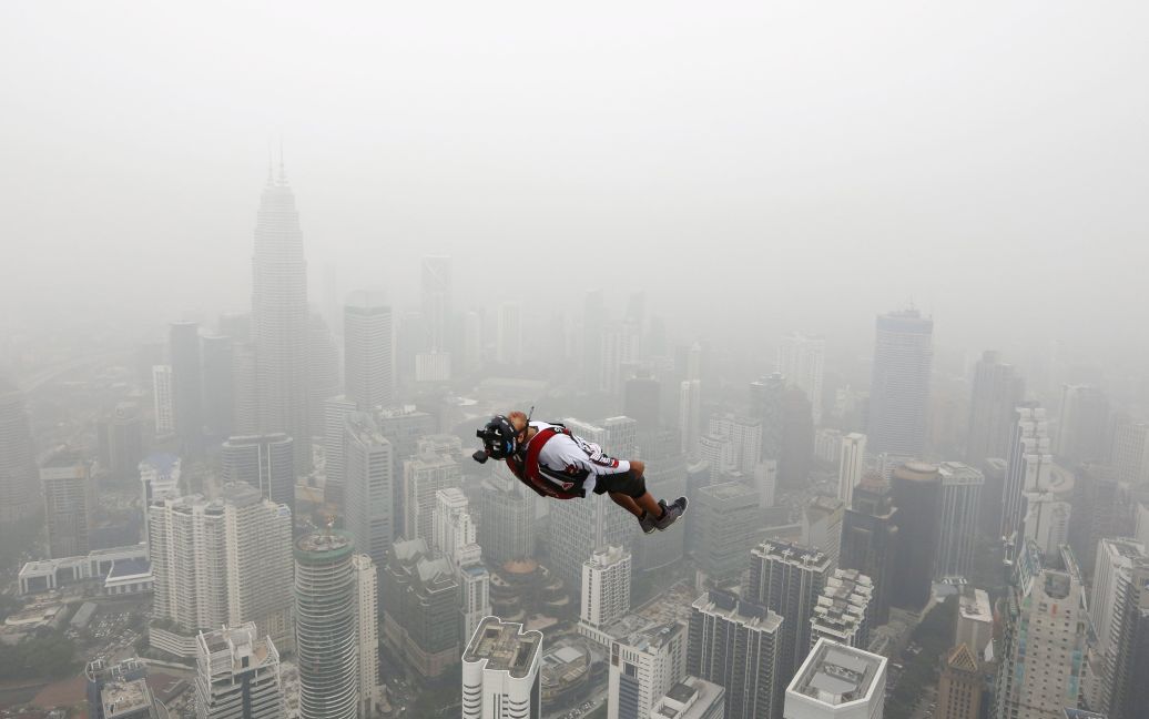 Бейс-джамер прыгает с 300-метровой башни в столице Малайзии Куала-Лумпур во время соревнований International Tower Jump. В этих соревнованиях принимают участие более 100 человек. Вокруг стелется дым от лесных пожаров в соседней Индонезии. / © Reuters
