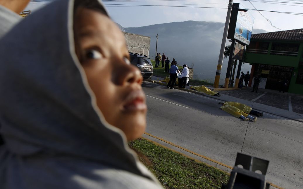 Ребенок смотрит на место преступления в городе Тегусигальпа, Гондурас. Перед тем неизвестные остановили автомобиль и застрелили четырех его пассажиров - отца, его двух сыновей и племянника. / © Reuters