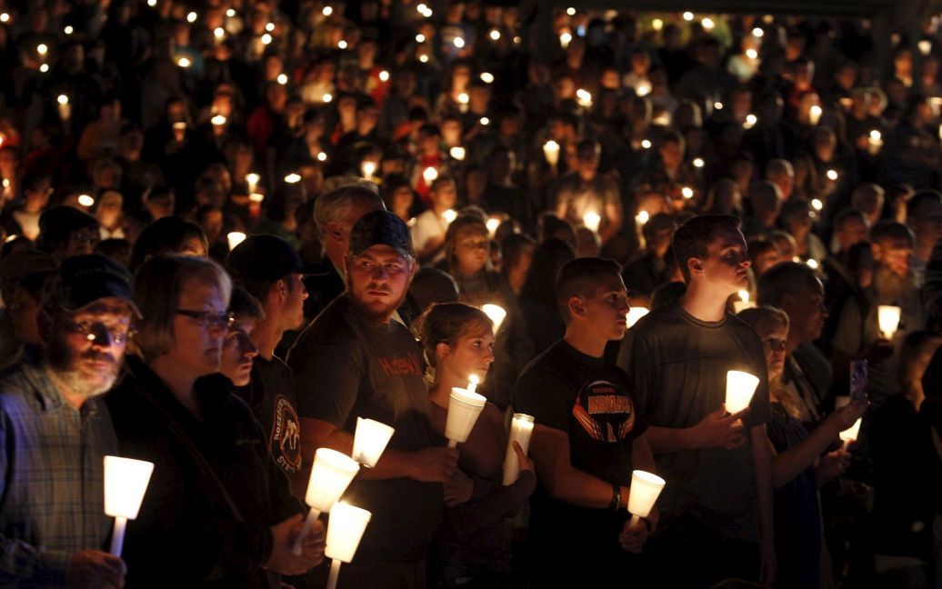 Люди участвуют в зажжении свечей в память о жертвах массового расстрела в колледже американского города Роузбург . 1 октября 26-летний стрелок открыл огонь в колледже, убив девять человек и ранив семерых других, прежде чем полиция застрелила его. / © Reuters