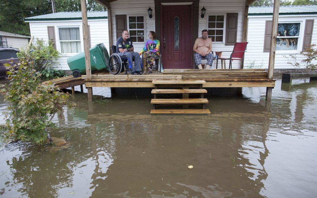 Люди сидят в окружении паводковых вод, окружающих их дом в городе Миртл-Бич, Южная Каролина. Мощный ливень вызвал наводнение в этом американском штате, в результате чего по меньшей мере восемь человек погибли. / © Reuters