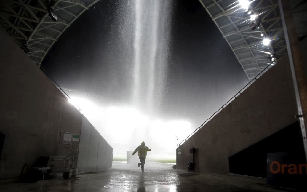 Человек убегает от сильного дождя во время футбольного матча чемпионата Франции между "Ниццей" и "Нантом". Из-за мощного ливня матч был прерван и перенесен на неопределенное время. К тому времени счет был 2:2. / © Reuters