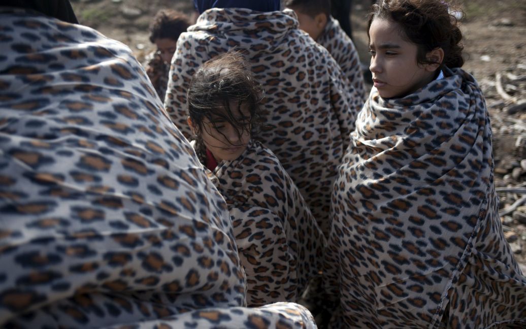 Сирийские девушки-беженцы завернуты в одеяла после того, как они прибыли на переполненной шлюпке на греческий остров Лесбос после пересечения Эгейского моря от турецкого побережья. По меньшей мере 430 000 беженцев и мигрантов прибыли в Европу через Средиземное море на лодках. / © Reuters