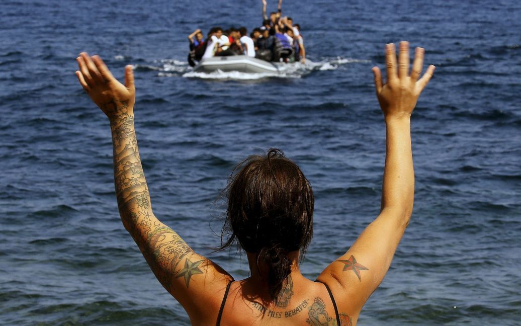 Волонтер сигналит шлюпке с афганскими мигрантами на пляже на греческом острове Лесбос. Лодка с беженцами пересекла Эгейское моря от турецкого побережья. / © Reuters