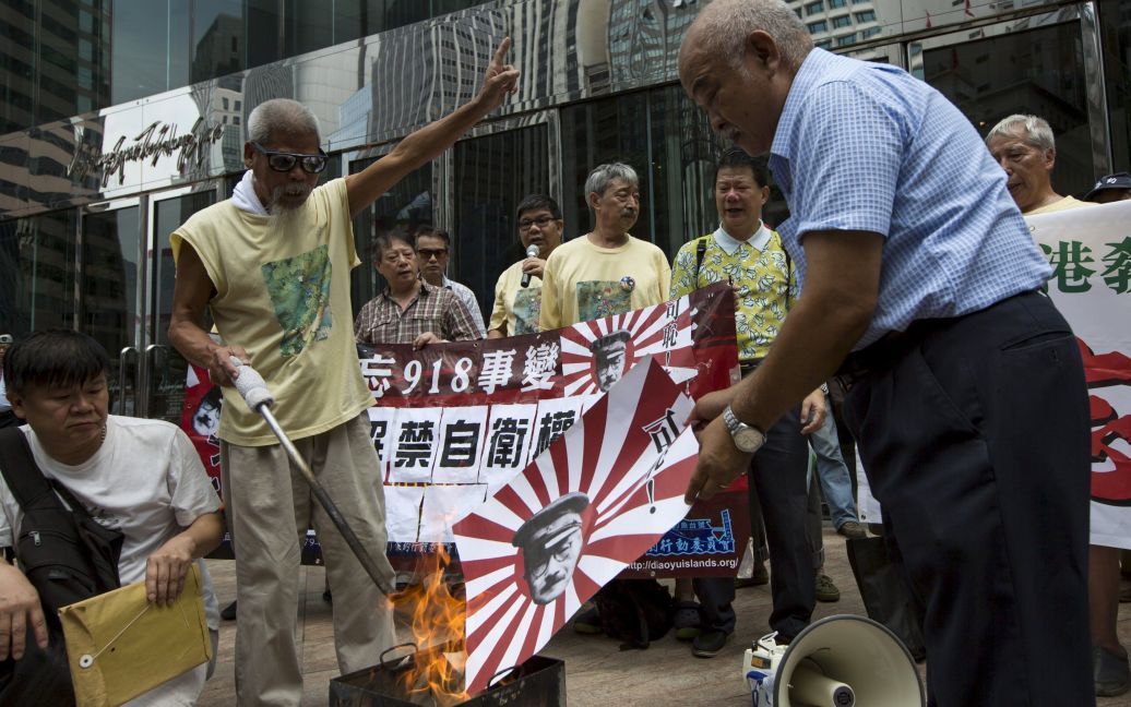Противники закона о расширении безопасности жгут флаг имперской Японии времен Второй мировой войны. / © Reuters