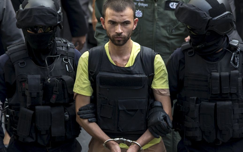 Полиция ведет подозреваемого в кровавом теракте 17 августа в Бангкоке. В субботу, 26 сентября, его привели на место теракта для процедуры инсценировки преступления. / © Reuters