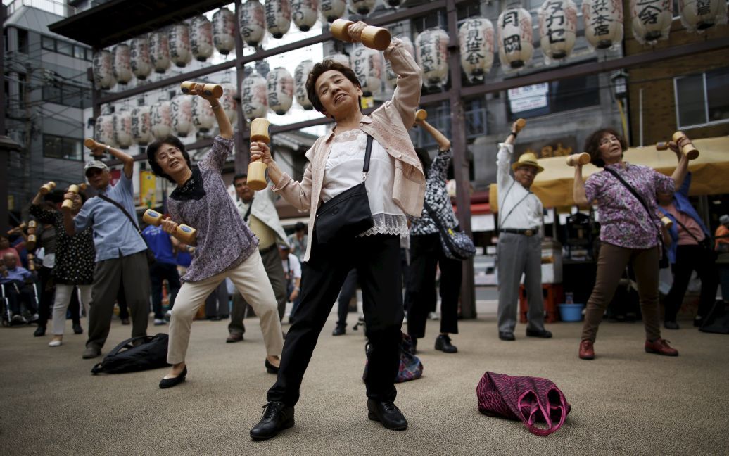 Люди среднего и пожилого возраста делают упражнения с деревянными гантелями, отмечая "День уважения престарелых" в Японии в храме в токийском районе Сугамо &mdash; этот район популярен среди японцев преклонного возраста. / © Reuters