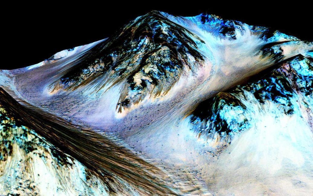 Темные образования шириной в пять и длиной около ста метров на Марсе. Ученые NASA пришли к выводу, что эти потоки, которые периодически образуются на "красной планете", могут быть образованы водой. / © Reuters
