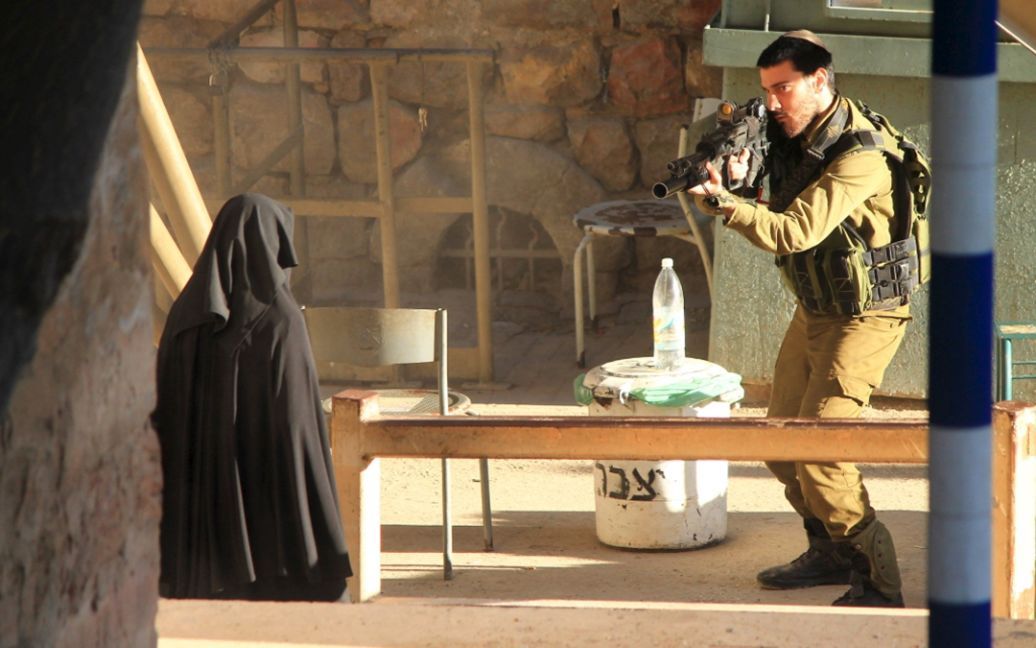 Израильский солдат направил ружье на 19-летнюю палестинку, прежде чем она была застрелена на контрольно-пропускном пункте в городе Хеврон. Израильские военные заявили, что расстреляли девушку после того, как она пыталась ударить ножом солдата. / © Reuters