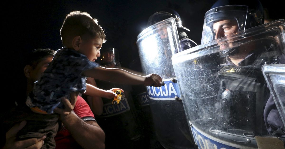 Мигрант держит ребенка перед словенскими полицейскими на границе между Хорватией и Словенией. Премьер-министр Словении Мирослав Церар заявил, что страна обсудит возможность введения &laquo;коридора&raquo; для прохождения мигрантов через страну, если их многочисленный поток будет слишком большим.