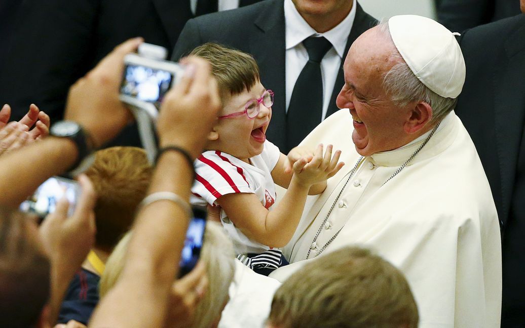 Папа Римский Франциск улыбается ребенку, которого взял на руки, во время аудиенции в Ватикане / © Reuters