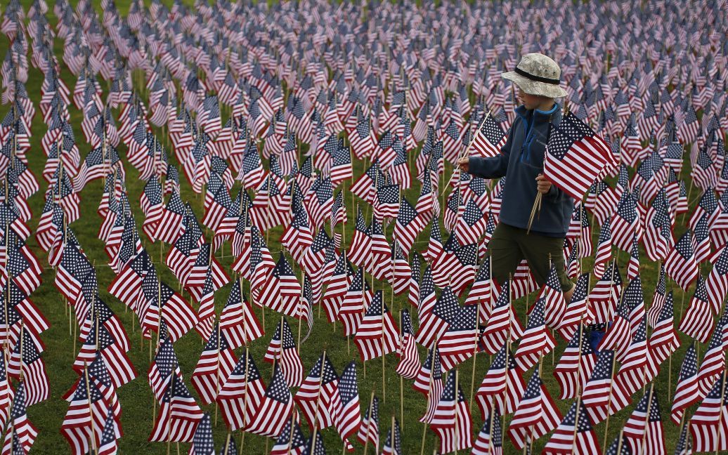 Мальчик ходит среди 3 000 флажков, помещенных в парке в городе Иллинойс в память о погибших в терактах 11 сентября 2001 года. В пятницу американцы отмечали 14 годовщину терактов 9/11. / © Reuters