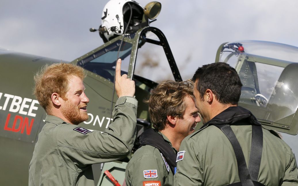 Британский принц Гарри шутит с пилотами после того, как они приняли участие в полете на самолетах Второй мировой в честь 75-летия воздушных боев за Британию. Таким образом чествуют летчиков, участвовавших в тех сражениях. / © Reuters