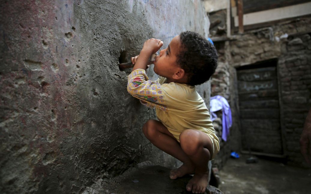 5-річний хлопчик п&#039;є воду з крану біля його будинку в трущобах Ешаш-ель-Судан в районі Гізи, що на південь від столиці Єгипту Каїра. Наприкінці серпня між жителями місцевих нетрів та поліцією відбулися сутички після того, як були знищені близько 50 старих хатин. Влада намагається очистити район від нетрів, жителі яких в основному займаються утилізацією сміття та випічкою хліба. / © Reuters