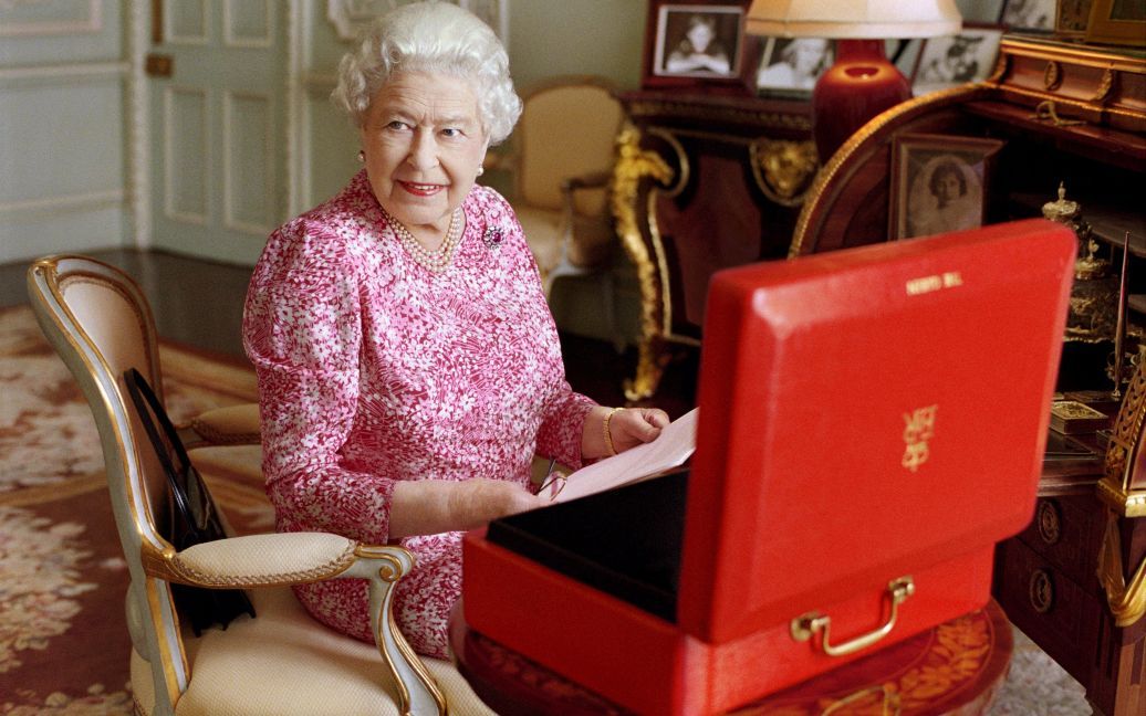 Королева Великобритании Елизавета II сидит в своей комнате в Букингемском дворце. В красном чемодане она хранит официальные документы. Елизавета II установила абсолютный рекорд длительности правления Великобританией. 89-летняя королева "побила" рекорд своей прабабушки, королевы Виктории, обогнав ее на один день и став монархом, который дольше всех правил страной &ndash; 63 года 7 месяцев и 2 дня (23 226 дней) / © Reuters